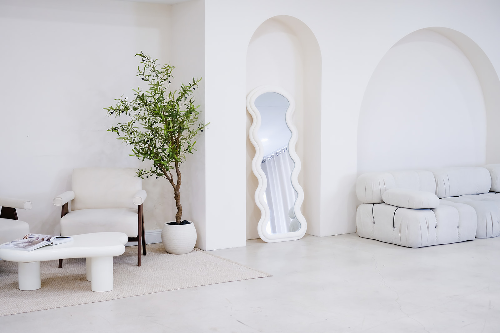 Natural-light lounge set with arches, a wavy mirror and boucle couches in a Miami content studio