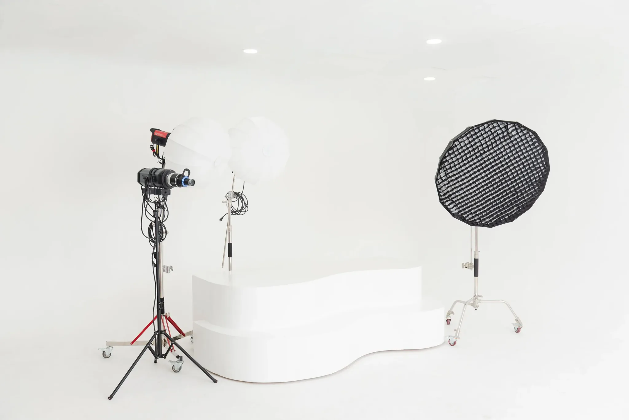 Curved posing platform centered on a white cyclorama wall, lit by studio softboxes in Miami