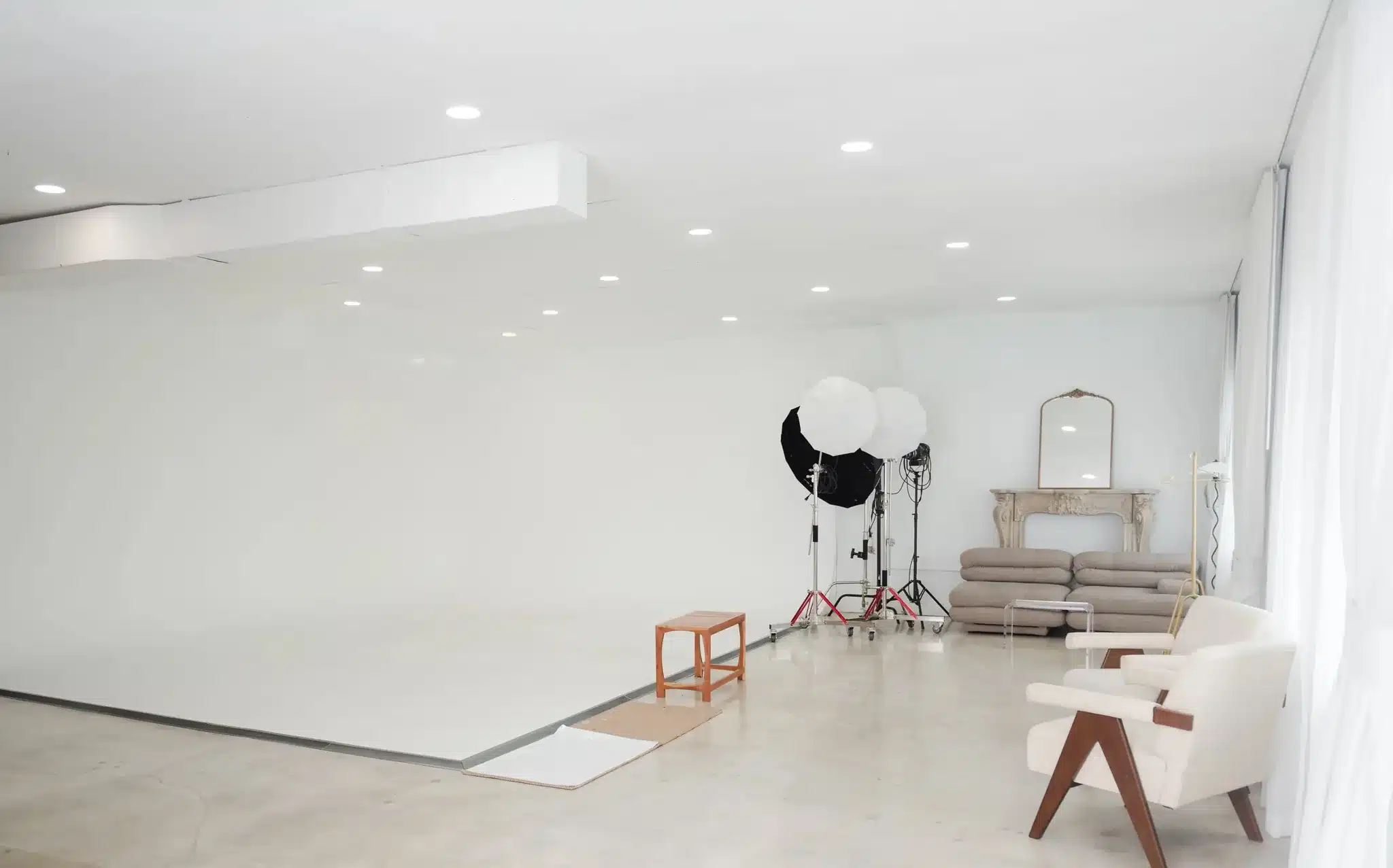 White cyclorama wall with umbrella strobe lighting and a lounge corner at a Miami studio