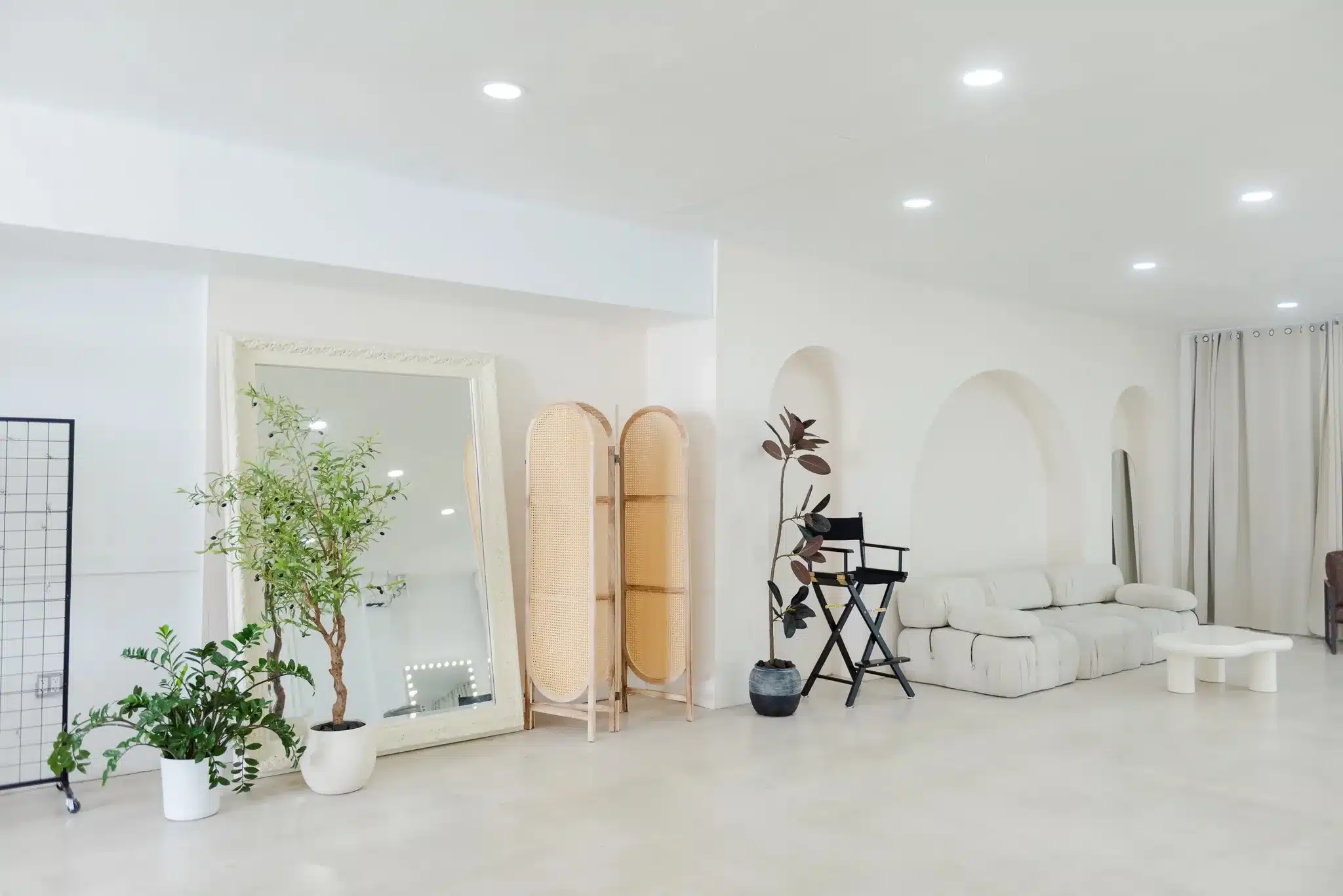 White glam lounge with a leaning floor mirror and arched niche wall in a Miami photo studio