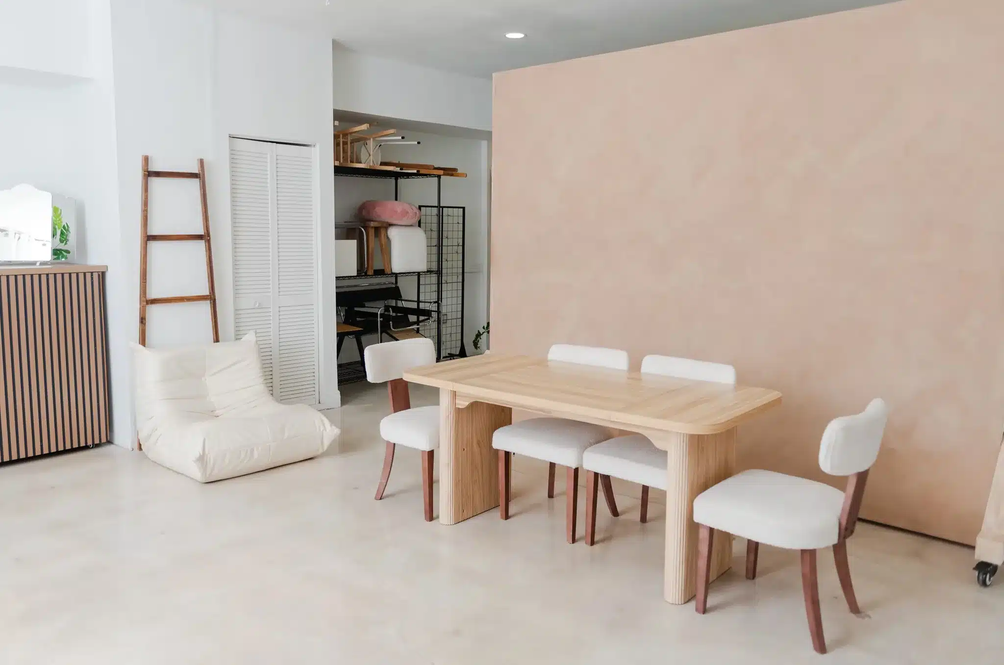 Dining table set with bouclé chairs in front of a peach plaster textured backdrop in Miami