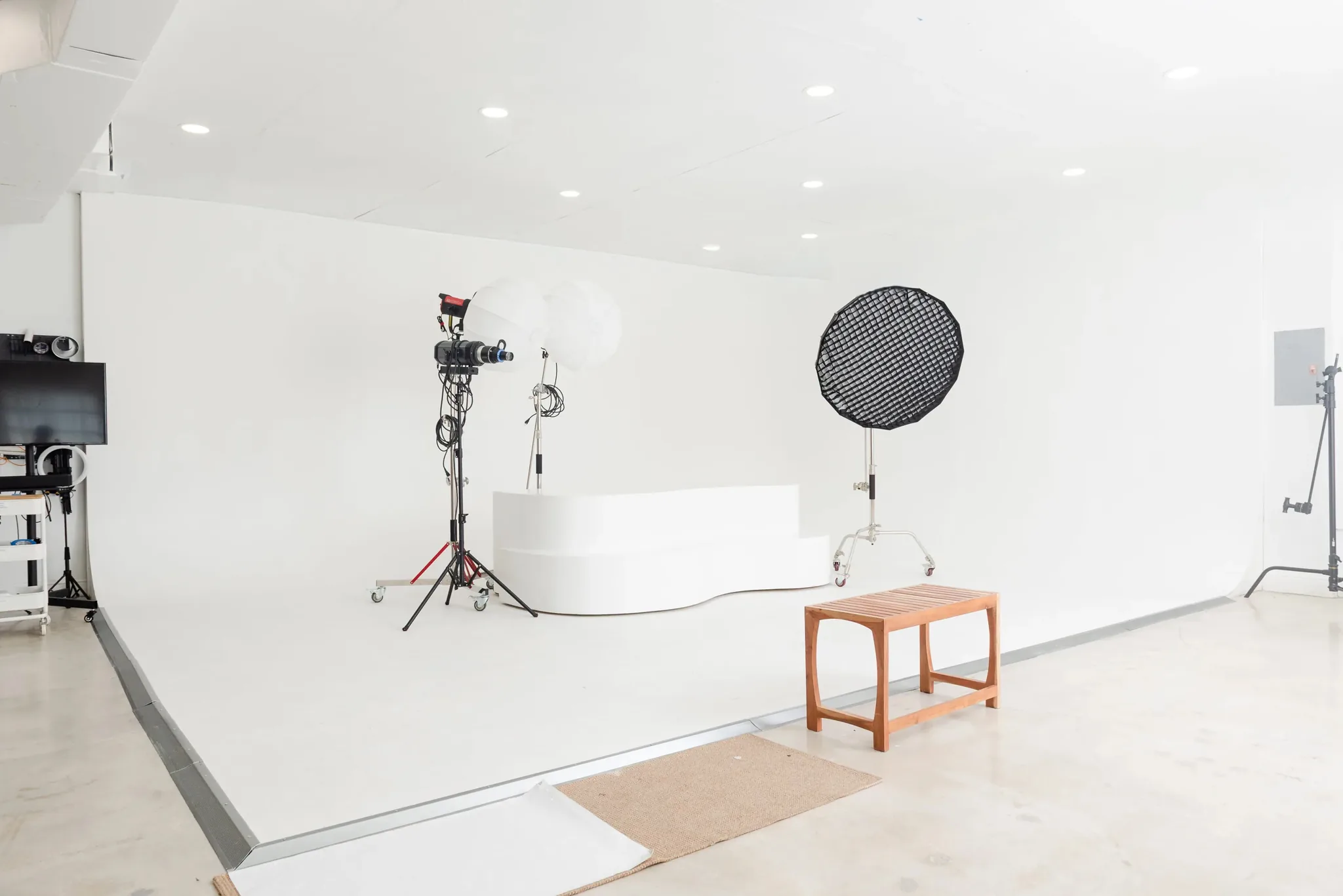 White cyclorama wall with a curved posing platform and studio lighting at a Miami photo studio