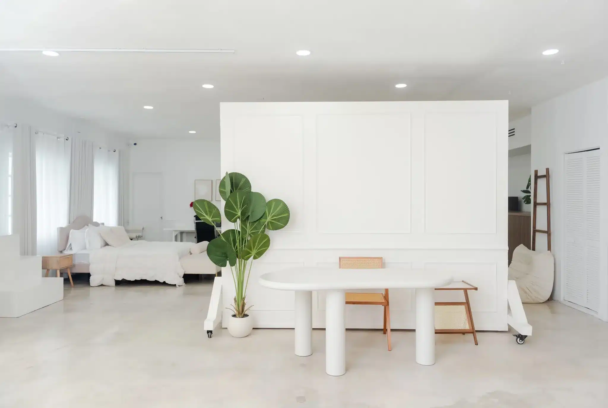 White paneled accent wall with a pedestal table and styled bedroom set in a Miami studio